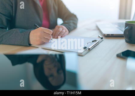 Geschäftsfrau unterzeichnen Vertrag, Reflexion über Tablet Computer im Büro Schreibtisch platziert
