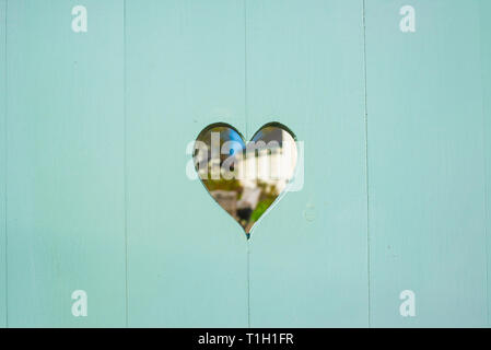 Herzförmige Tür Bohrung auf einem pastell Matt vintage Pale Blue Holz garten Tür Stockfoto