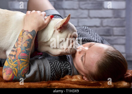 Französische Bulldogge auf den Händen seines Meisters. Es ist der Ansicht, dass die Mädchen ihre PET- und Umarmungen liebt und ihn küssen. Stockfoto