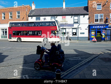 Bus- und Frau auf Mobilität scooter, Market Weighton, East Yorkshire, England, Großbritannien Stockfoto