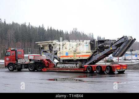 Mariehamn, Finnland - 23. März 2019: Rot Volvo FH 520 Auflieger von Konekuormaus Seppanen Oy hols Metso Lokotrack LT1110 Schlagkörper Anlage. Stockfoto