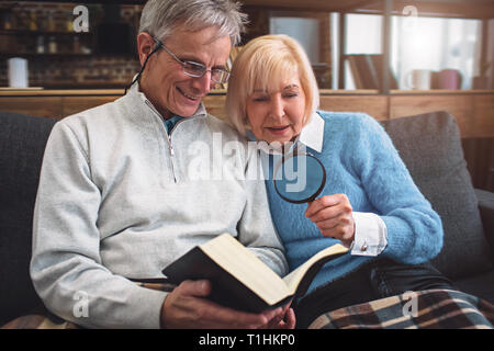 In der Nähe von altes Ehepaar, ein Buch zu lesen. Er ist mit Brille für r Stockfoto