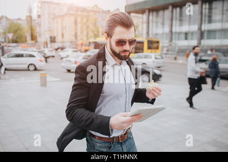 Viel beschäftigter Mann ist in Eile, hat er keine Zeit, er wird Snack auf der Essen zu gehen. Arbeitnehmer essen, trinken Kaffee, telefonieren, gleichzeitig Stockfoto