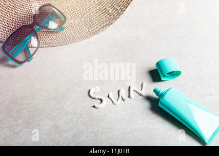 Sonnenschutzmittel auf grauem Hintergrund, flach. Frühling und Sommer Schutz vor der Sonne Stockfoto
