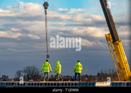 Mitarbeiter, die über den Bau eines Mehrfamilienhauses. Bauarbeiten auf den Hausbau. Saison der Feder. Stockfoto