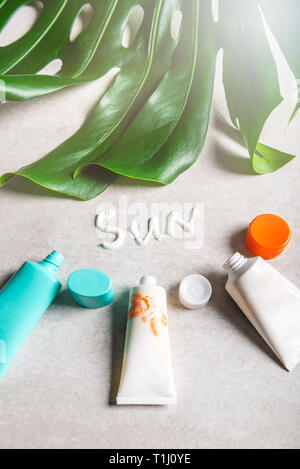 Sonnenschutzmittel auf grauem Hintergrund, flach. Frühling und Sommer Schutz vor der Sonne Stockfoto