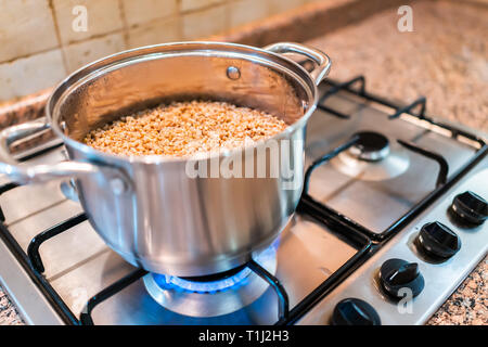 Nahaufnahme von buchweizen Kochen im Topf auf dem Herd in der Küche mit blauen Erdgas Flamme und Korn kasha gekocht Stockfoto