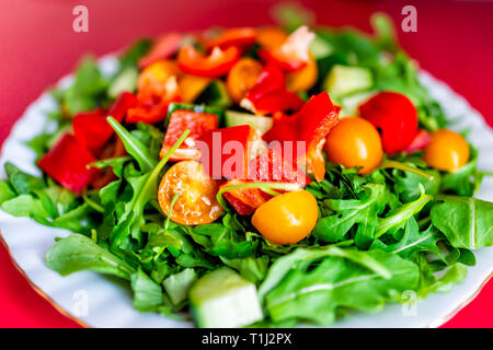 Closeup Makro von frisches rohes gehacktes Gemüse Salat mit Rucola grünen Rot und Orange Paprika Tomaten auf dem Tisch bunte lebendige gesundes Mittagessen mich Stockfoto