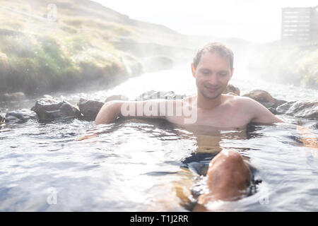 Mann baden in Hveragerdi Reykjadalur Hot Springs im Herbst morgen Tag im Süden Islands auf golden circle Felsen und Fluss Dampf Stockfoto