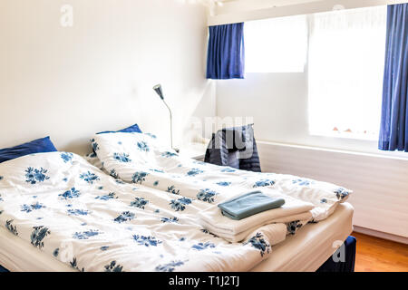 Sauber europäischen Doppelzimmer französisches Bett mit Daunendecke Tischleuchten, dekorative blaue Kissen im Schlafzimmer Home Haus typische Wohnung Handtücher in Hostel Hotel Stockfoto