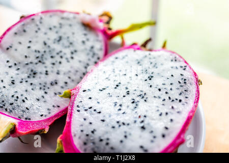 Closeup Makro von Schneiden Sie die rosa lila Dragon drachenfrucht Fruchtschnitten Hälften Hälfte innen weiß Fleisch Samen von Fenster Cactus Stockfoto