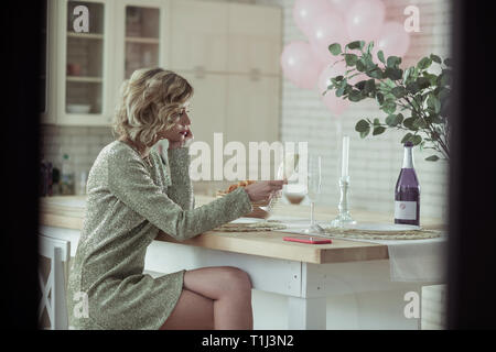 Elegante Frau in der Küche und trinken Champagner sitzen Stockfoto