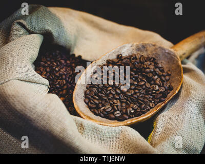 In der Nähe von frisch gerösteten Kaffeebohnen im Beutel mit Löffel aus Holz. Stockfoto