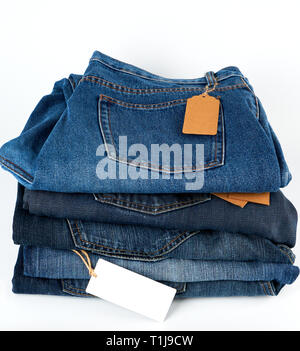 Stapel gefalteter blaue Jeans mit leeren Tags auf einen weißen Hintergrund, Nahaufnahme Stockfoto