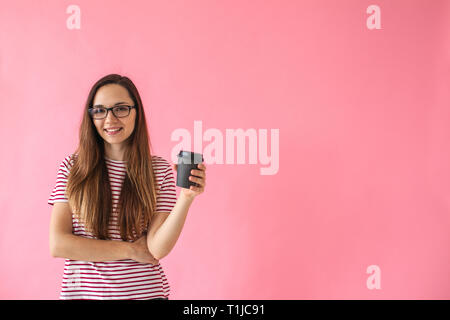 Schönen Lächeln positive Mädchen trinkt Kaffee auf einem rosa Hintergrund. Kaffeepause. Stockfoto