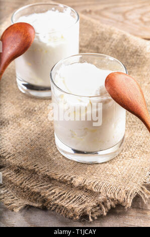 Zwei Gläser der traditionellen Joghurt stehen auf sackleinen Serviette auf Holztisch. Stockfoto