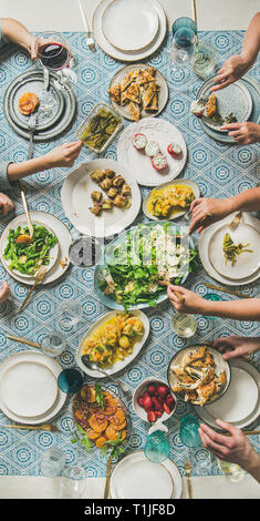 Mediterranes Abendessen und menschlichen Händen hält Getränke und Essen Stockfoto