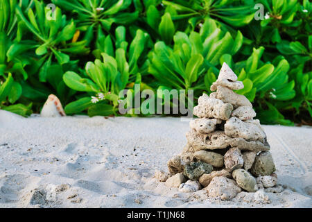 Dieses Bild zeigt einen Stein Pyramide mit üppigen grünen Pflanzen im Hintergrund. Die Pyramide wurde in den Malediven gebaut Stockfoto