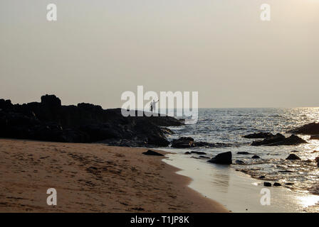 Touristische Angeln auf dem felsigen Strand von Anjuna, Goa, Indien Stockfoto