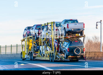 Big Rig industrial grade Gelb klassische Motorhaube car hauler Semi Truck Transport Autos auf zwei Ebenen Auflieger auf die Überführung der Straße fahren mit pr Stockfoto