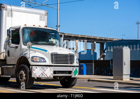 Mittelklasse compact Tag cab weiß Semi Truck mit Box Anhänger ausgestattet für brennbare und chemische Stoffe, die für die lokalen Lieferungen, die auf dem Tragen Stockfoto