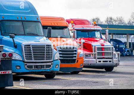 Verschiedene Motorhaube Marken und Modelle der professionellen big Rigs semi Trucks mit kommerziellen Ladung auf Auflieger in Reihe stehen auf dem Flurförderzeug Stockfoto