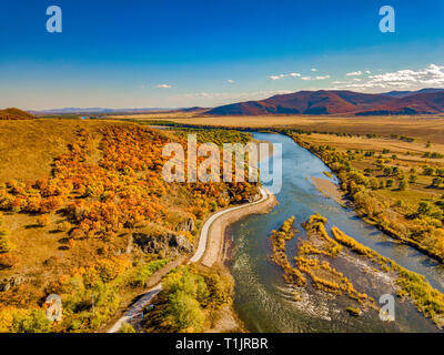 Luftaufnahme des mäandernden Fluss gegen Berge und Wiesen mit blauer Himmel im Herbst in der Inneren Mongolei, China Stockfoto