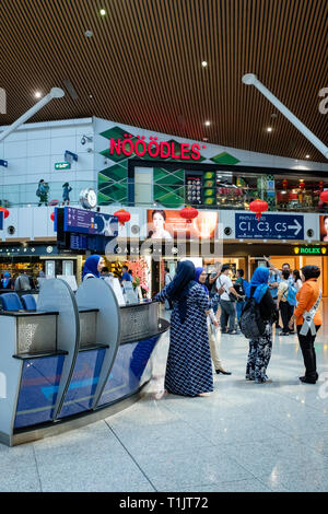 Internationale Reisende überprüfen ihre Flüge am Kuala Lumpur International Airport. Stockfoto