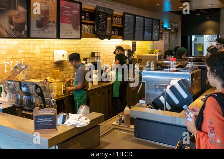 Baristas und Café Mitarbeiter arbeiten hart, als Reisende greifen Sie schnell einen Kaffee bei Starbucks Lounge in der KL Stockfoto