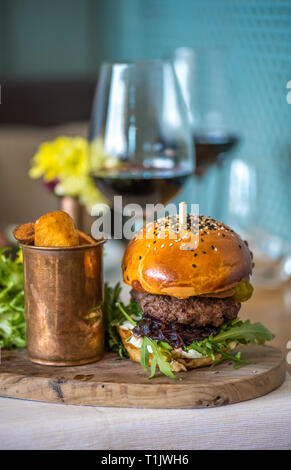 Ein amerikanisches Rindfleisch Burger mit Bratkartoffeln und Rotwein Stockfoto