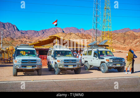 DAHAB, Ägypten - Dezember 16, 2017: Safari Tour weg Straßen am Straßenrand Bedouin Cafe mit viw auf die steinige Wüste Berge im Hintergrund geparkt werden Stockfoto