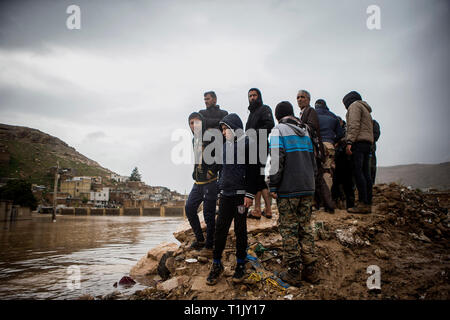 Shiraz, Iran. 26 Mär, 2019. Die Leute stehen auf Rückstände nach einer Flut von starken Regenfällen in Schiraz, Iran, 26. März 2019 verursacht. Mindestens 25 Menschen wurden bei dem starken Regen und der anschließenden Überschwemmungen im Iran in der vergangenen Woche getötet. Credit: Ahmad Halabisaz/Xinhua/Alamy leben Nachrichten Stockfoto