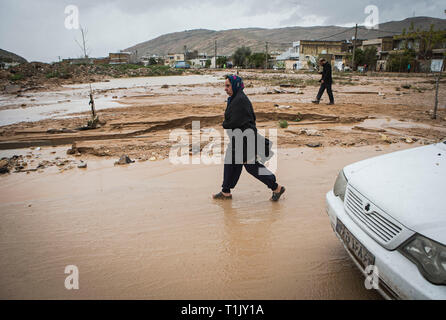 Shiraz, Iran. 26 Mär, 2019. Eine Frau geht in den Schlamm nach einer Flut von starken Regenfällen in Schiraz, Iran, 26. März 2019 verursacht. Mindestens 25 Menschen wurden bei dem starken Regen und der anschließenden Überschwemmungen im Iran in der vergangenen Woche getötet. Credit: Ahmad Halabisaz/Xinhua/Alamy leben Nachrichten Stockfoto