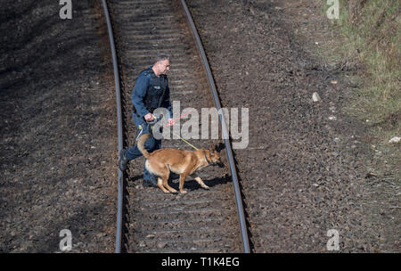 Wiesbaden, Deutschland. 27 Mär, 2019. Ein hundeführer Spaziergänge über die Gleise mit seinem Absondernde Hund. Besuchen Sie die Website nahm aufgrund der massiven Sicherheitsvorkehrungen statt. Hier Ali B., ein Eingeborener von Irak, sagte vergewaltigt auf die 14-jährige Susanna haben, dann tötete sie und vergrub ihr Körper. Credit: Boris Roessler/dpa/Alamy leben Nachrichten Stockfoto