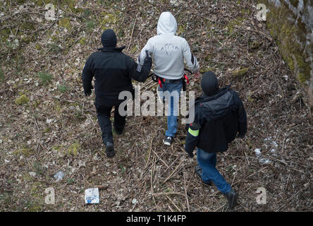 Wiesbaden, Deutschland. 27 Mär, 2019. Von zwei maskierten Polizisten begleitet, Ali B., warf der Ermordung der 14-jährige Susanna, ist entlang einer Bahnstrecke in der Nähe von Erbenheim geführt. Hier der Mann, der aus dem Irak stammen, angeblich das Mädchen vergewaltigt und dann getötet und begraben ihren Körper. Credit: Boris Roessler/dpa/Alamy leben Nachrichten Stockfoto