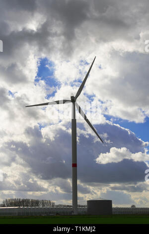 Eine Windmühle durch dramatische Wolken, die den blauen Himmel verstecken umgeben Stockfoto