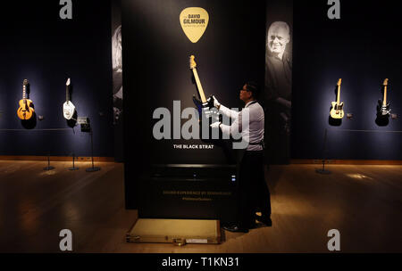 Eine Kunst handler greift die 1969 schwarze Fender Stratocaster Solid Body E-Gitarre während einer Vorschau der pre-sale Wanderausstellung des Persönlichen guitar Collection von Pink Floyd David Gilmour bei Christie's in London. Stockfoto