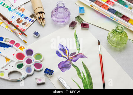 Aquarell Zeichnung - Iris Blume - und künstlerische Ausstattung auf dem Schreibtisch. Ansicht von oben. Stockfoto