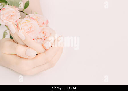 Trendy zarter Frühling Maniküre. Weibliche Hände mit Nail Design holding Tee Rosen auf hellen Hintergrund. Kopieren Sie Platz. Stockfoto