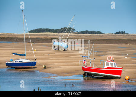 Bunte Boote marooned auf Sandbänken bei Ebbe im Osten Flotte Mündung an der Brunnen neben dem Meer, North Norfolk Coast, East Anglia, England, UK. Stockfoto