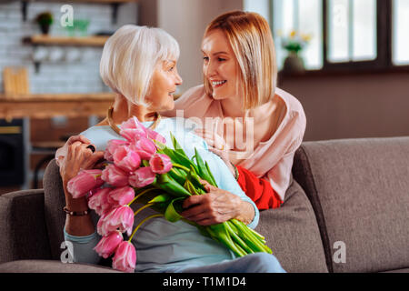 Attraktive Tochter zärtlich auf älteren d-lächelnde Mutter Stockfoto