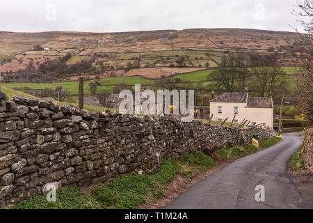 Malerische Aussicht auf eine kurvenreiche Straße führt von Reeth Dorf im Swaledale zeigt Fjälls, Stein, Mauerwerk und Häuser Stockfoto