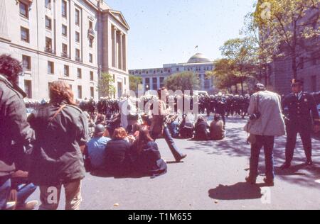 Während der 1971 Tag der Proteste gegen den Vietnamkrieg, die Demonstranten in Hippie Kleidung in der Mitte des 10. ST NW sitzen, an einem sonnigen Tag, mit Blick auf eine große Anzahl von Polizeibeamten, in Washington, DC, Mai 1971. () Stockfoto