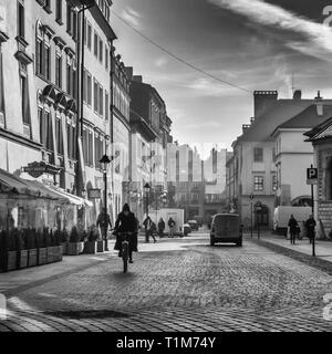 Lokale Frau auf einem Fahrrad, plac maryacki morgen früh auf und die Strahlen des dramatischen Sun, Krakau Polen Stockfoto