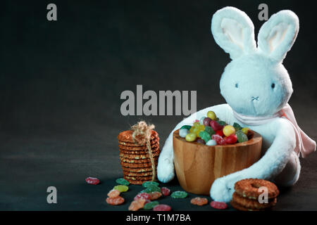 Weiches, weißes Kaninchen im Studio mit Süßigkeiten und Kekse. Stockfoto