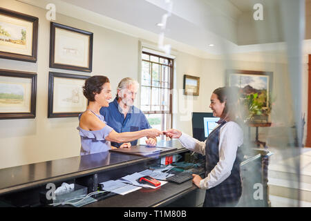 Reifes Paar Einchecken an der Rezeption Stockfoto