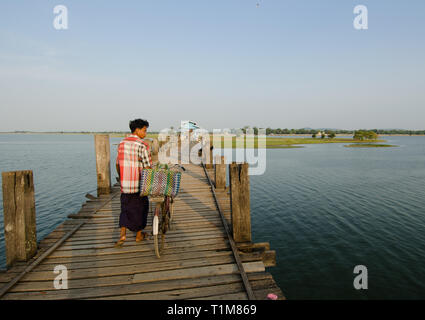 MANDALAY, MYANMAR - 3 Jan 2014: ein Mann schiebt sein Fahrrad auf dem hölzernen Plattform des berühmten U-Bein Brücke, Mandalay, Myanmar. Dies ist die längste hölzerne Br Stockfoto