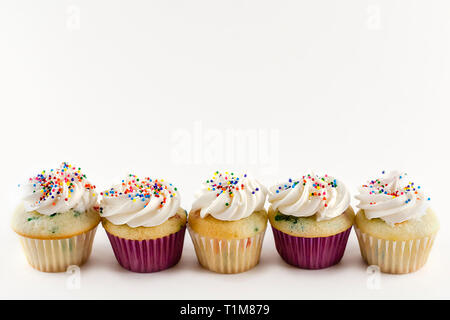 Fünf mini Muffins in einer Reihe auf weißem Hintergrund. Konfetti Kuchen mit weißer Zuckerglasur mit Rainbow Streuseln. Kopieren Raum über. Stockfoto