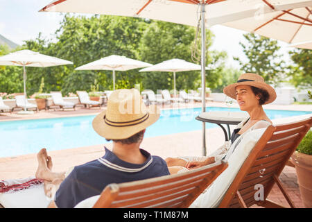 Paar entspannen auf Liegestühlen im Resort Pool Stockfoto