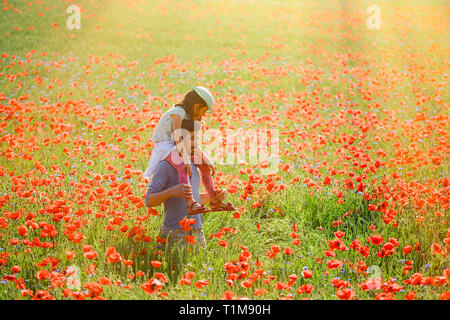 Vater trägt Tochter auf Schultern in sonnigen idyllischen ländlichen Feld mit roten Mohnblumen Stockfoto